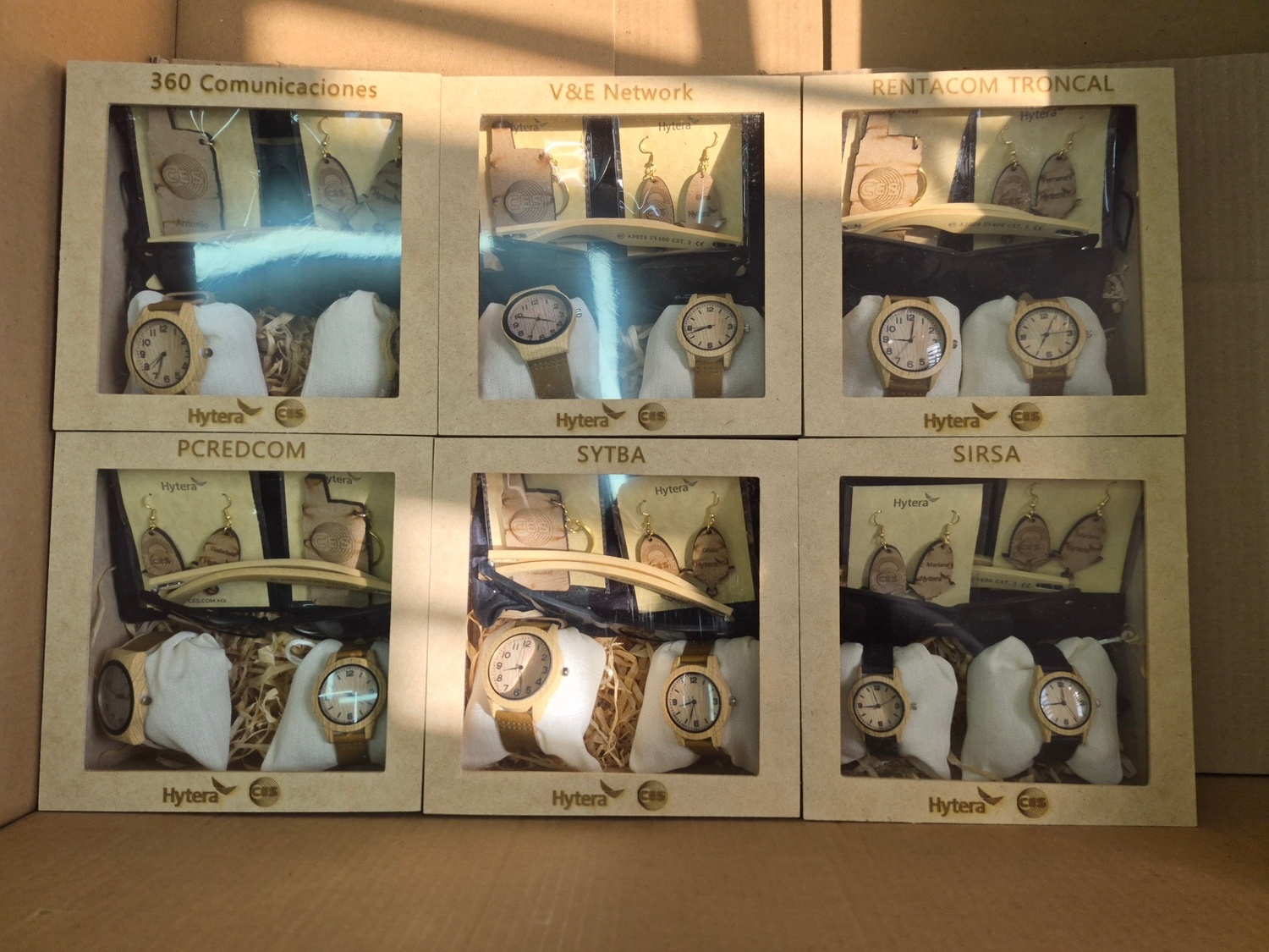 Relojes y llaveros de madera grabados con logotipos de distintas empresas, en cajas personalizadas